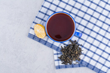 Cup of tea on tablecloth with lemon slice