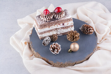 Slice of cake with Christmas ornaments on wood piece