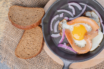 Fried egg on pan with bread and onion slices