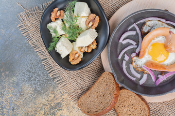 Fried egg on pan and cheese bowl with walnut kernels