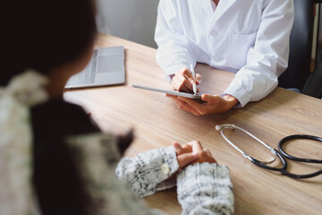 Portrait of a doctor advising clients on health issues holding a tablet to work and talking to patients who come to treatment