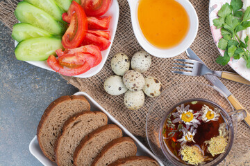 Obraz na płótnie Canvas Breakfast table with vegetables, tea, bread and eggs