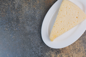 Slice of yellow cheese on white plate