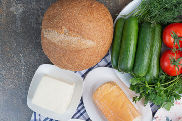 Various cheese, vegetables and bread on tablecloth