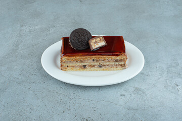 Slice of caramel cake with biscuit on white plate