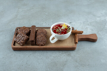 Chocolate biscuits and cup of tea on wooden board