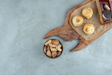 Cake and pastries on wooden board with nuts