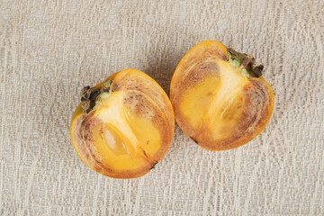 Two half cut slices of persimmons on burlap