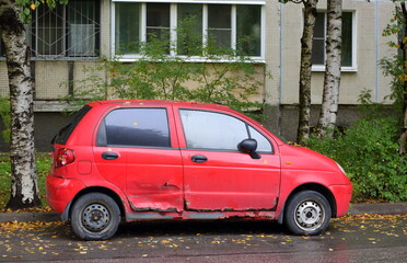An old rusty broken red car is parked on the street, Iskrovsky Prospekt, St. Petersburg, Russia, September 2022