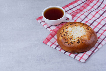 Cheese pastry on tablecloth with cup of tea