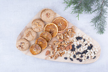 Biscuits, oranges and various nuts on wooden board