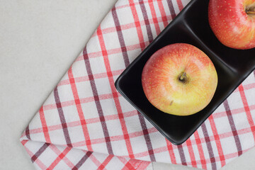 Whole red apples on black plate with tablecloth