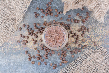 A cup of delicious coffee with coffee beans on wooden board