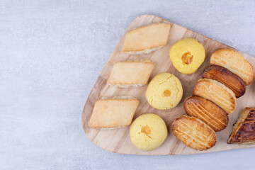 Variety of tasty cookies on wooden board