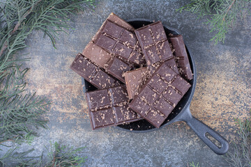 A dark pan full of sliced chocolates on marble background