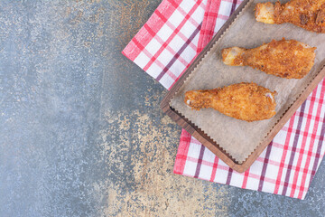 Grilled chicken drumsticks on wooden board with tablecloth