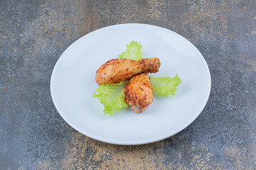 Grilled chicken drumsticks on plate with lettuce