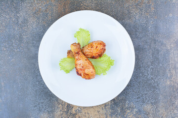Grilled chicken drumsticks on plate with lettuce