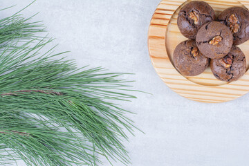 Chocolate cookies with walnut kernels on wooden plate
