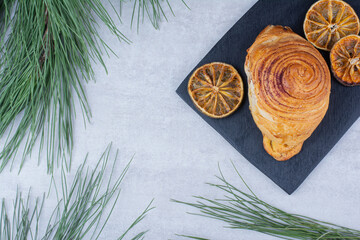 Delicious pastry with dried orange slices on black board