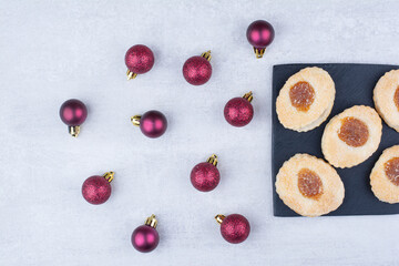 Cookie with jam on black board with glittery balls