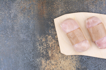 Raw chicken breasts on wooden board