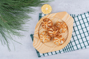 Coconut macaroons on wooden plate with half cut lemon