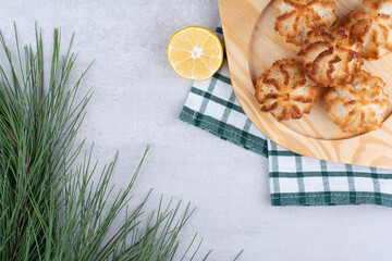 Coconut macaroons on wooden plate with half cut lemon