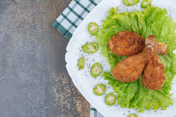 Chicken drumsticks with pepper and lettuce on white plate
