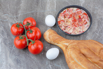 Fresh tomatoes with fried eggs and bread on marble background