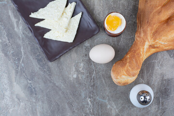 Boiled egg with fresh white bread on marble background