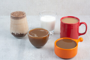 Various delicious coffee cups and milk on stone background