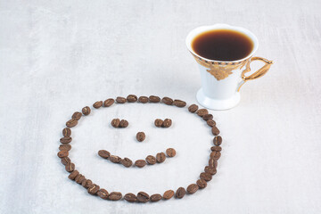 Cup of coffee and coffee beans formed like face