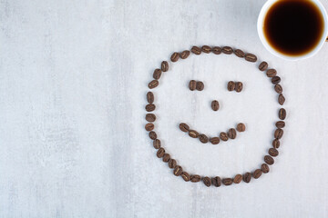 Cup of coffee and coffee beans formed like face