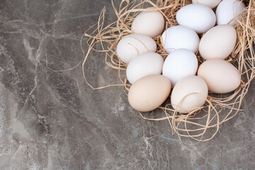 Several chicken fresh eggs on hay on marble background