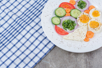 Tasty boiled eggs with spices and vegetables on tablecloth
