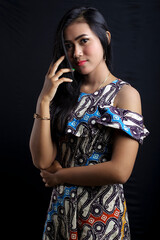 smiling young Asian woman wearing batik clothes isolated on black background. Batik Day.