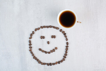 Cup of coffee and coffee beans formed like face