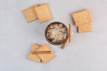 A cup of delicious drink with crackers and cinnamon sticks