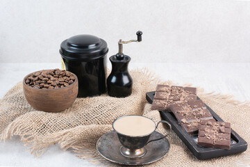 Coffee, chocolate bar and coffee beans on burlap