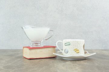 Cup of coffee with milk and book on marble table