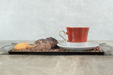 Cup of coffee with beans and cookies on plate