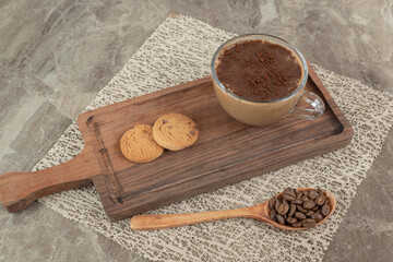 Cup of hot coffee, biscuits on wooden board with coffee beans