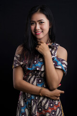 smiling young Asian woman wearing batik clothes isolated on black background. Batik Day.