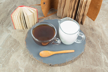 Cup of coffee, spoon and milk on wood piece