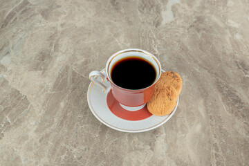 Cup of coffee with cookies on marble background