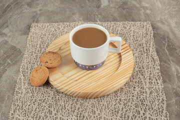 Cup of coffee and biscuits on wooden plate
