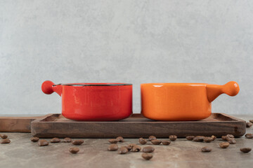 Two cups of coffee on wooden board with coffee beans