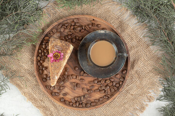 Slice of cake, coffee and coffee beans on wooden plate