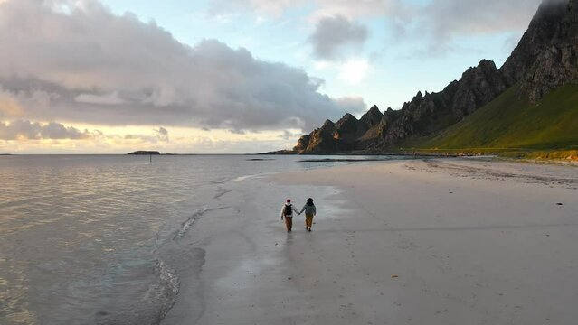 ouple hiking on sandy beach. Village on Andoya Blake Island. Vesteralen Archipelago, Norway aerial